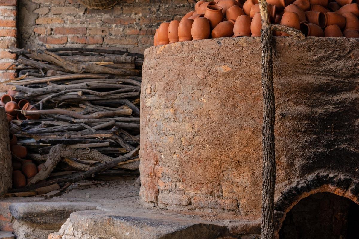 Authentic wood-fired oven used for traditional Greek baking, surrounded by terracotta and stacked wood