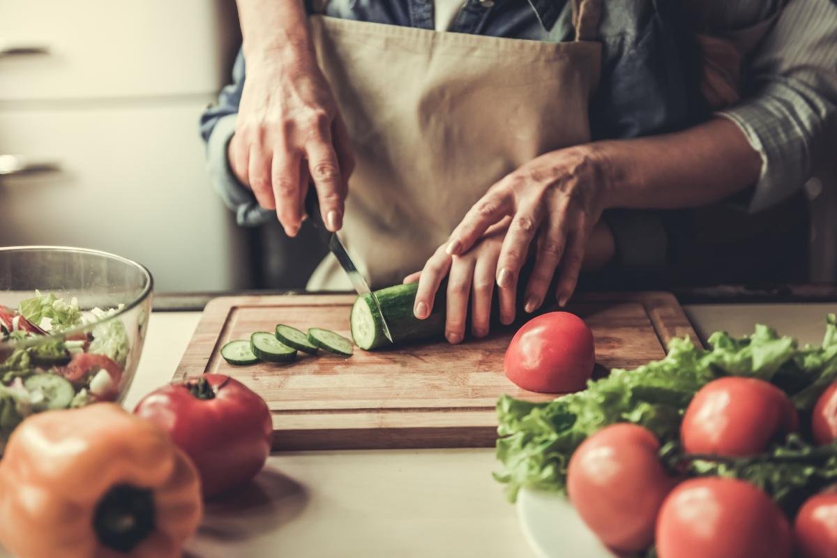 Mother and child preparing a Mediterranean meal together with fresh tomatoes and herbs on a rustic wooden counter
