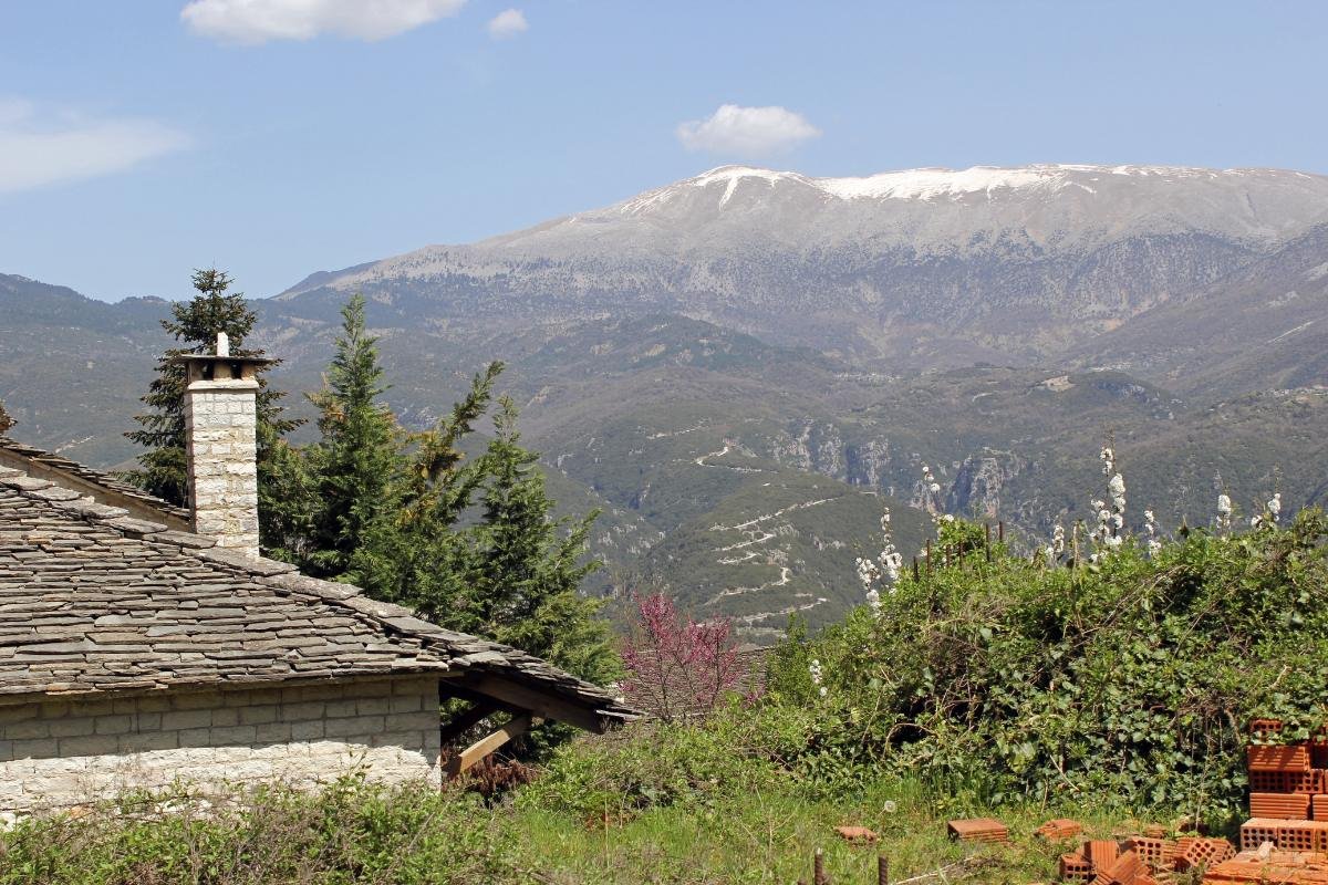 Traditional stone house in Epirus with tea-covered mountains in the background