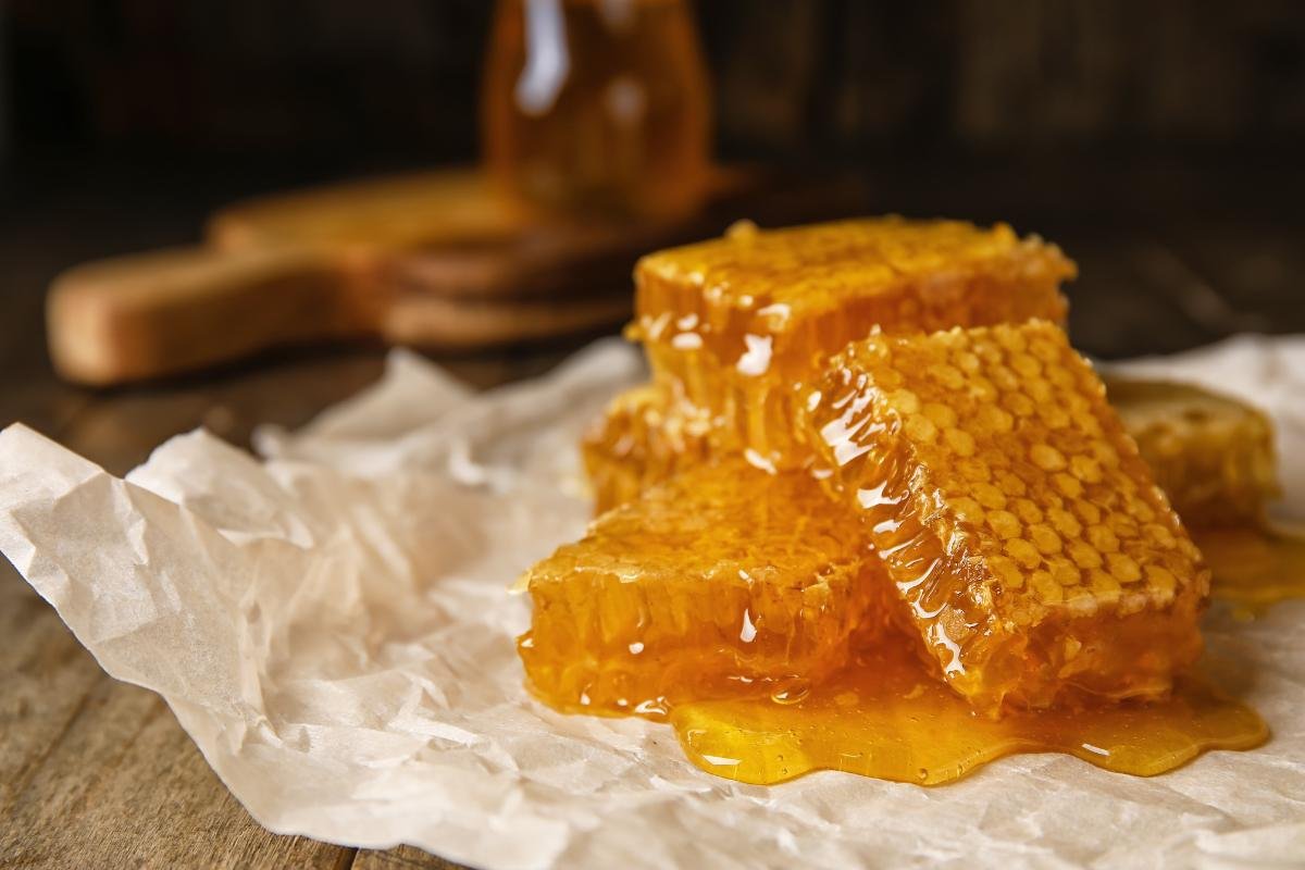 Raw honeycomb placed on wax paper with rustic lighting