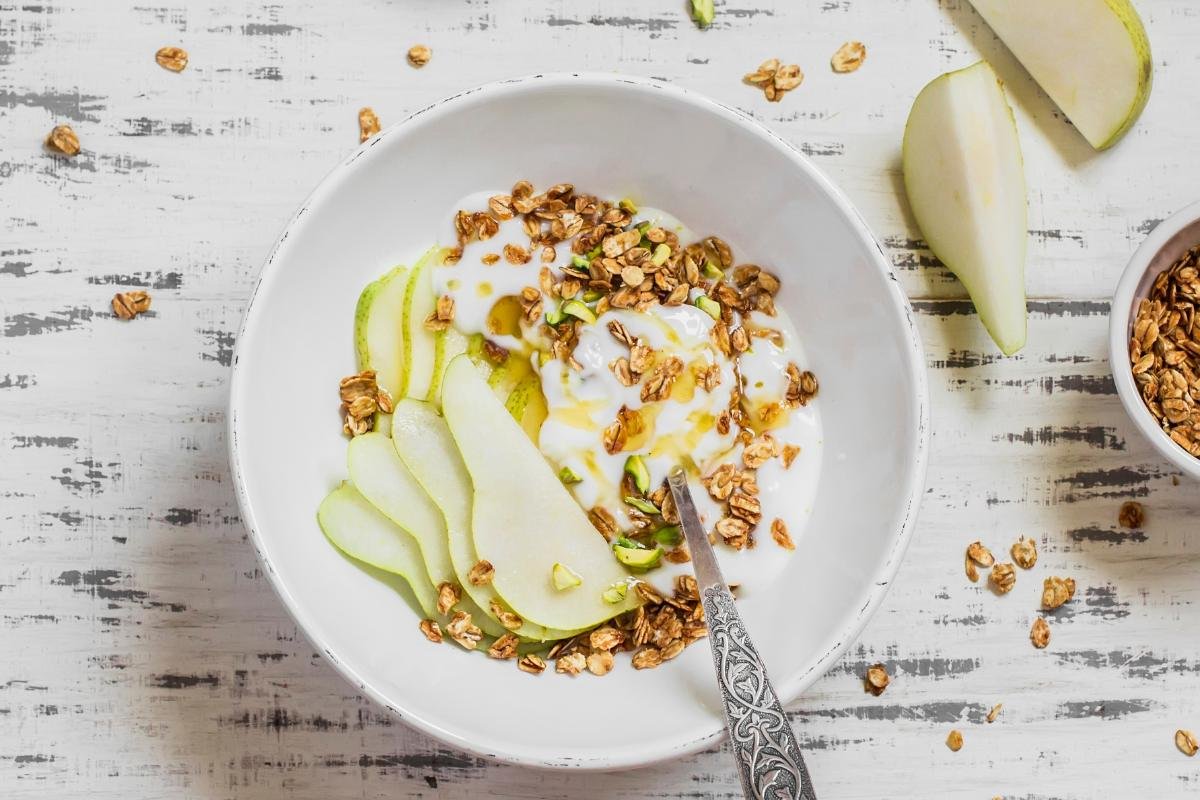Bowl of thick Greek yogurt with apple slices and a drizzle of honey