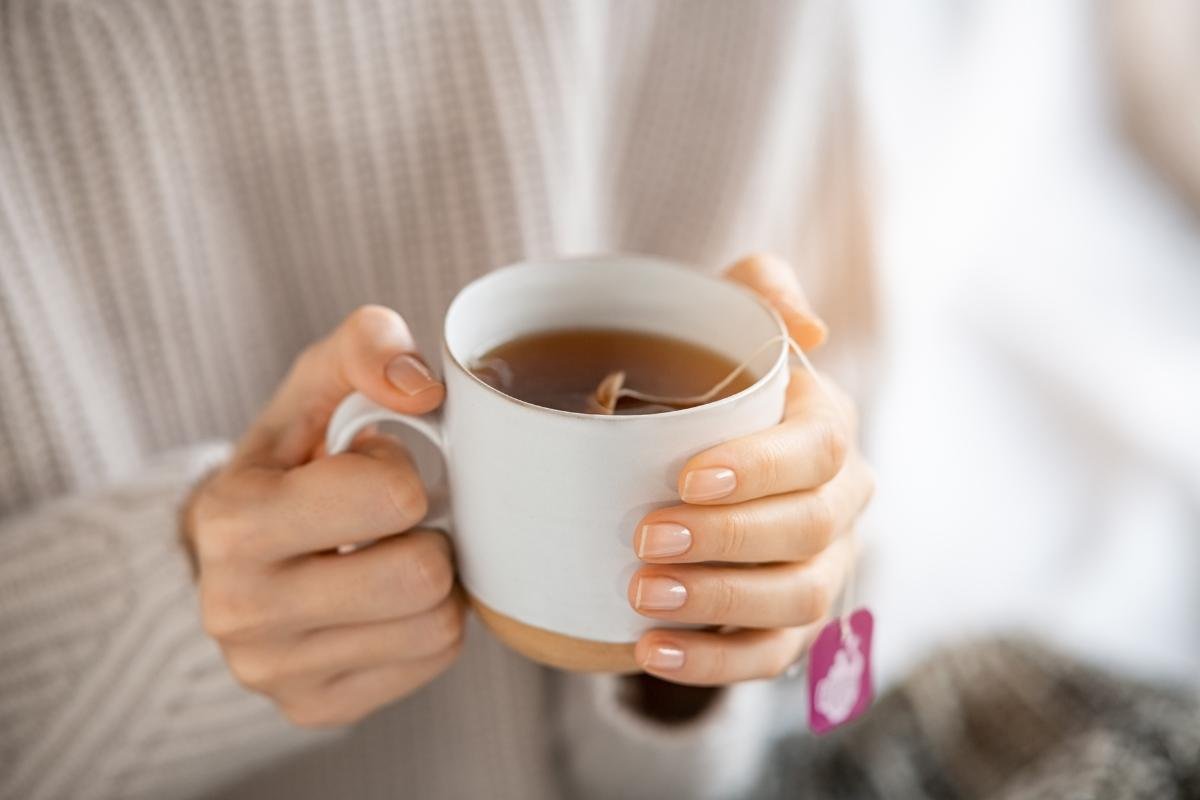 Woman in soft sweater holding a hot cup of herbal Greek mountain tea