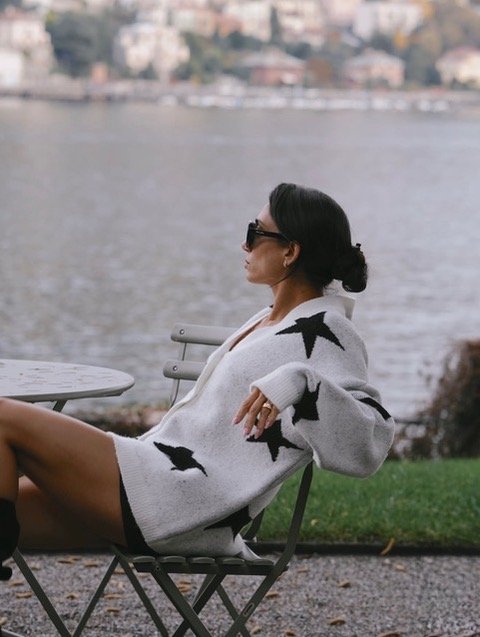Woman setting on a chair wearing a stylish wool outerwear close to the mediterranean sea