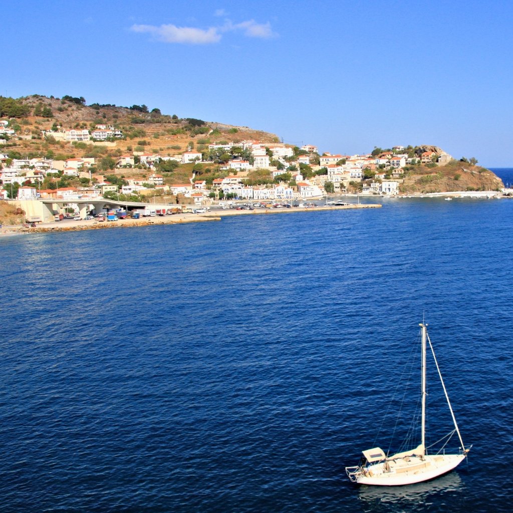 A view of the Ikaria coastline and village, surrounded by the deep blue Aegean Sea, symbolizing peaceful living.