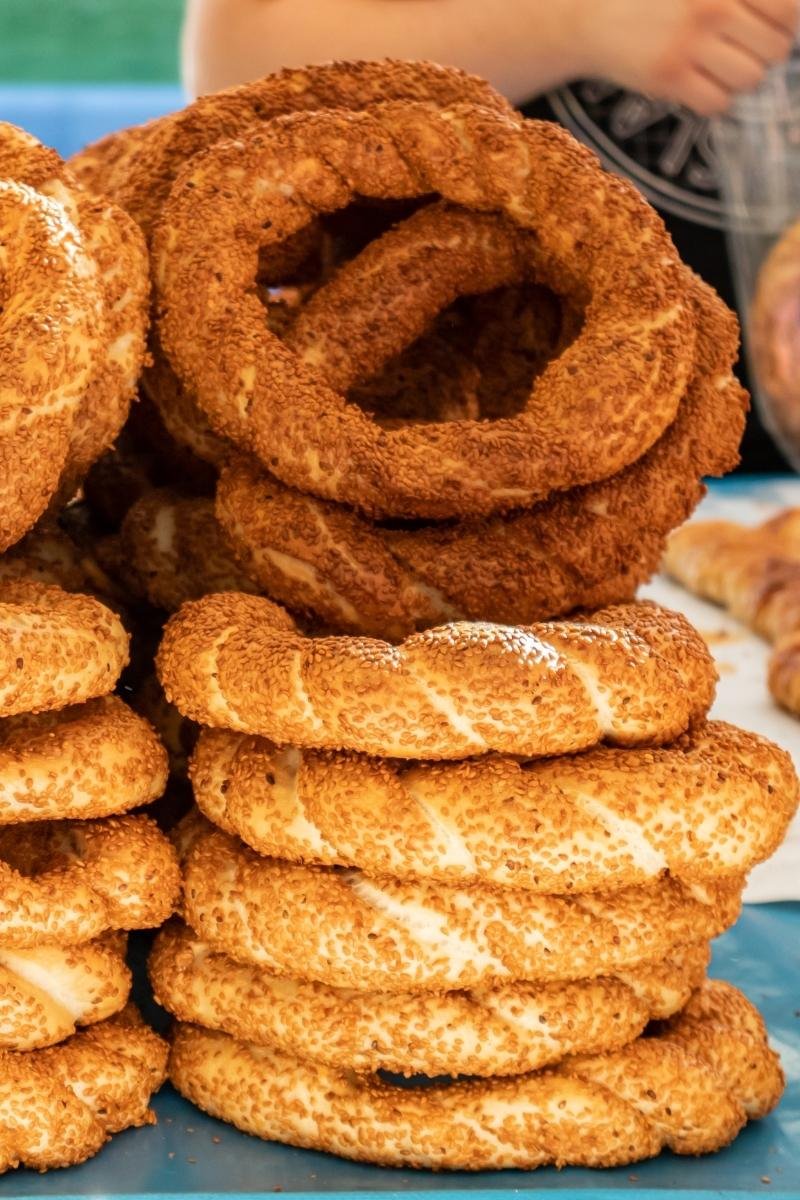 A tall stack of fresh Thessaloniki Koulouri, a traditional sesame-crusted bread ring found in the city's historic markets.